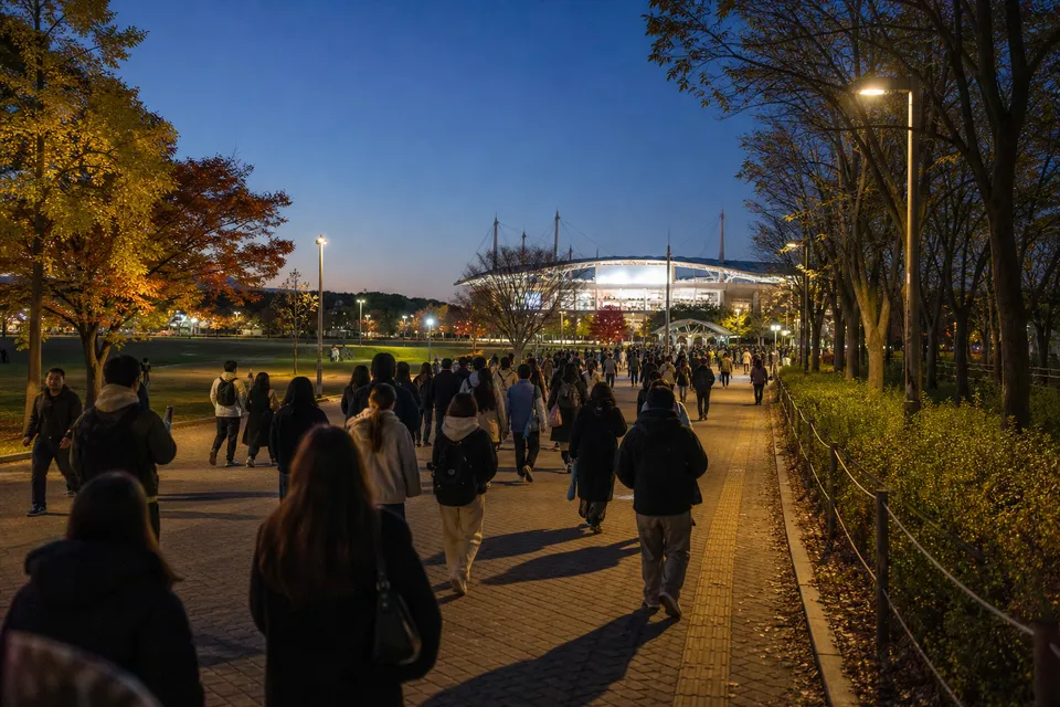 Concertgoers crossing Seoul Olympic Park toward KSPO DOME on an autumn evening