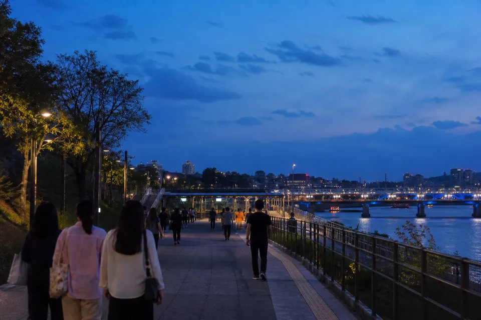 Visitors leaving along the Han River path on Nodeul Island after a Seoul concert at night