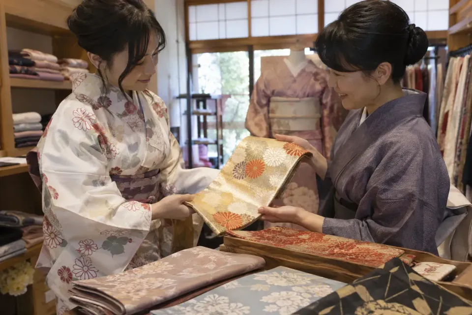 一位旅行者正在京都一家和服店挑選腰帶顏色。