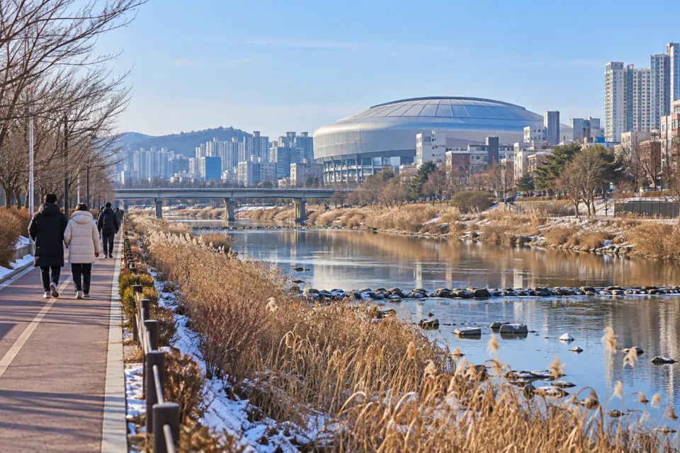 AI-generated travel illustration of an Anyangcheon winter walking path near Gocheok and the dome