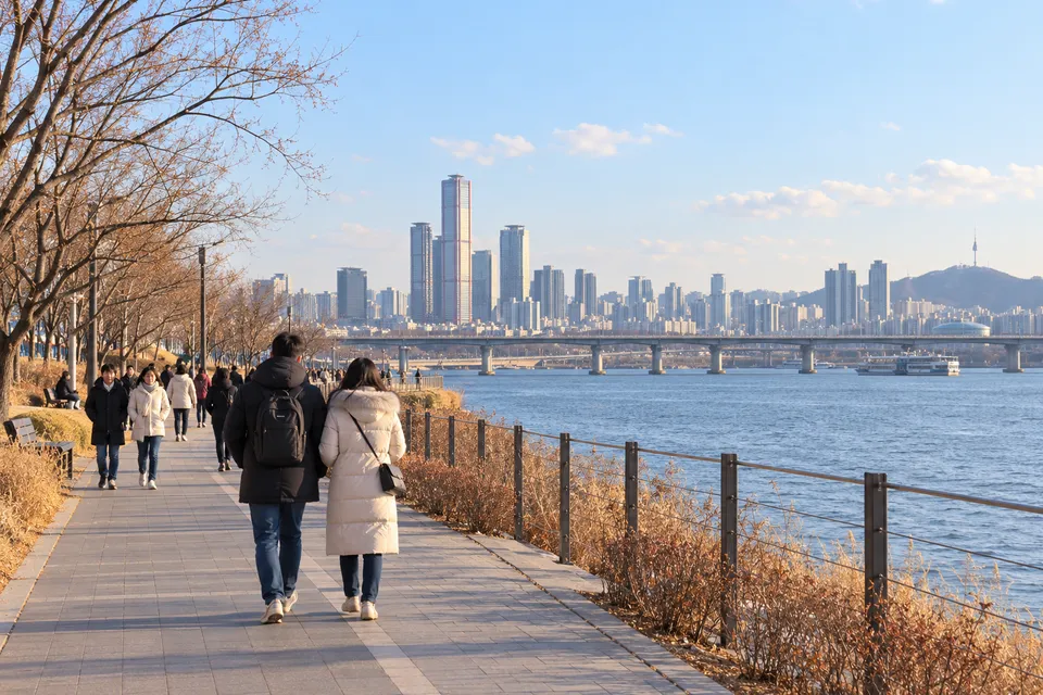 AI illustration of travelers walking beside the Han River on a winter afternoon