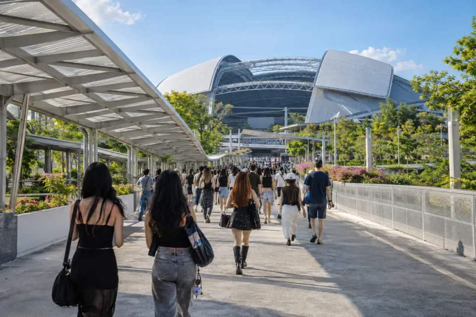 Editorial illustration of visitors walking along the sheltered approach to Singapore National Stadium